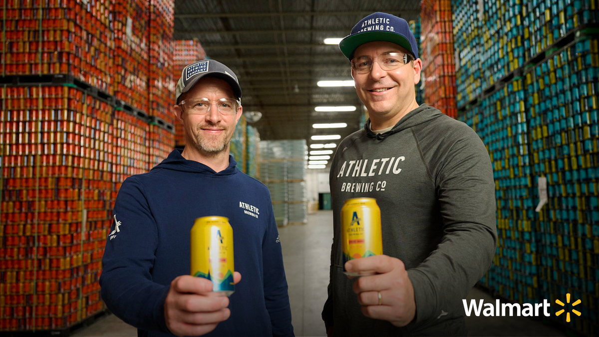 Two guys holding a beer can in a beer warehouse