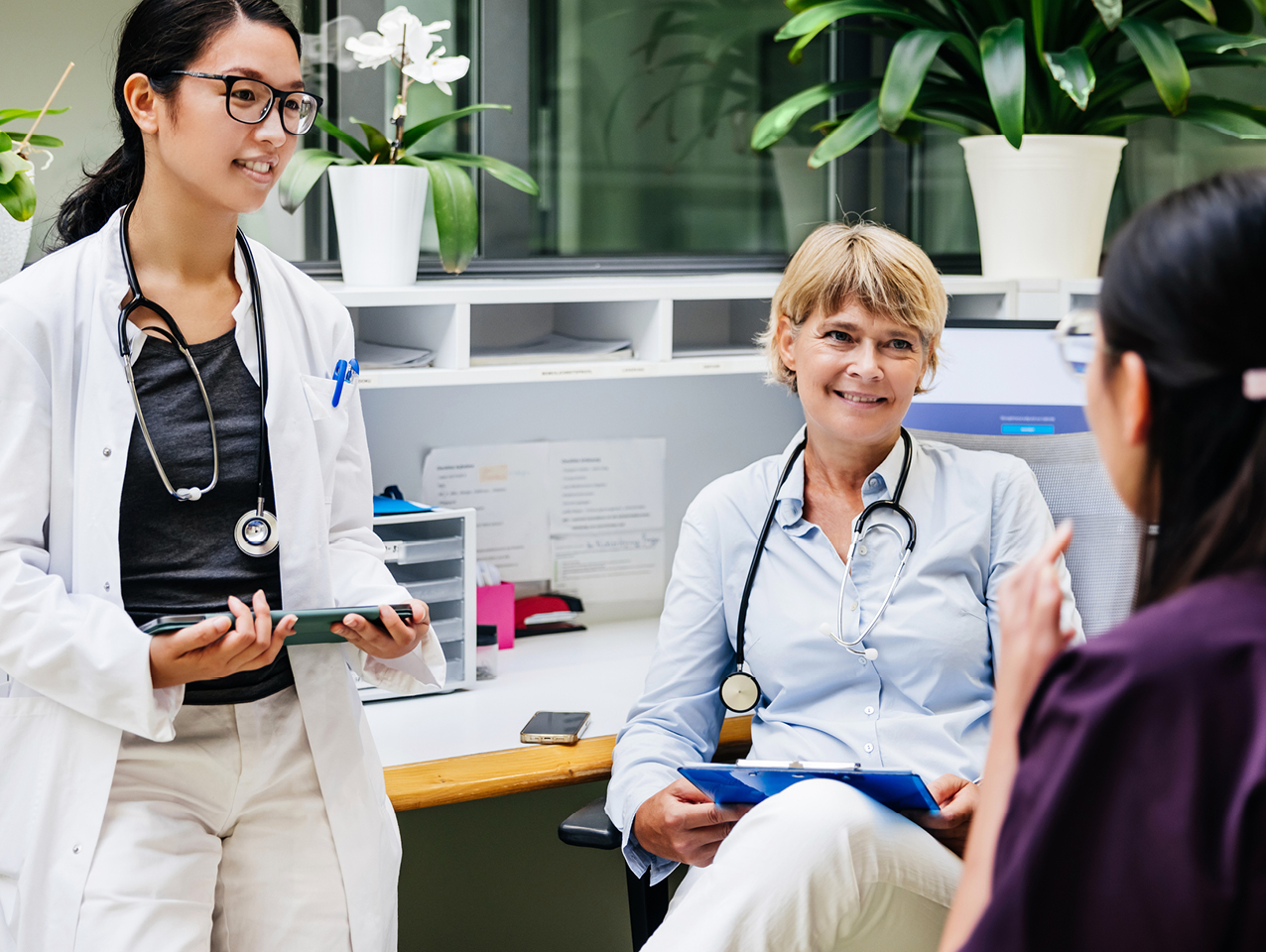 Two doctors holding tablets while talking to a nurse