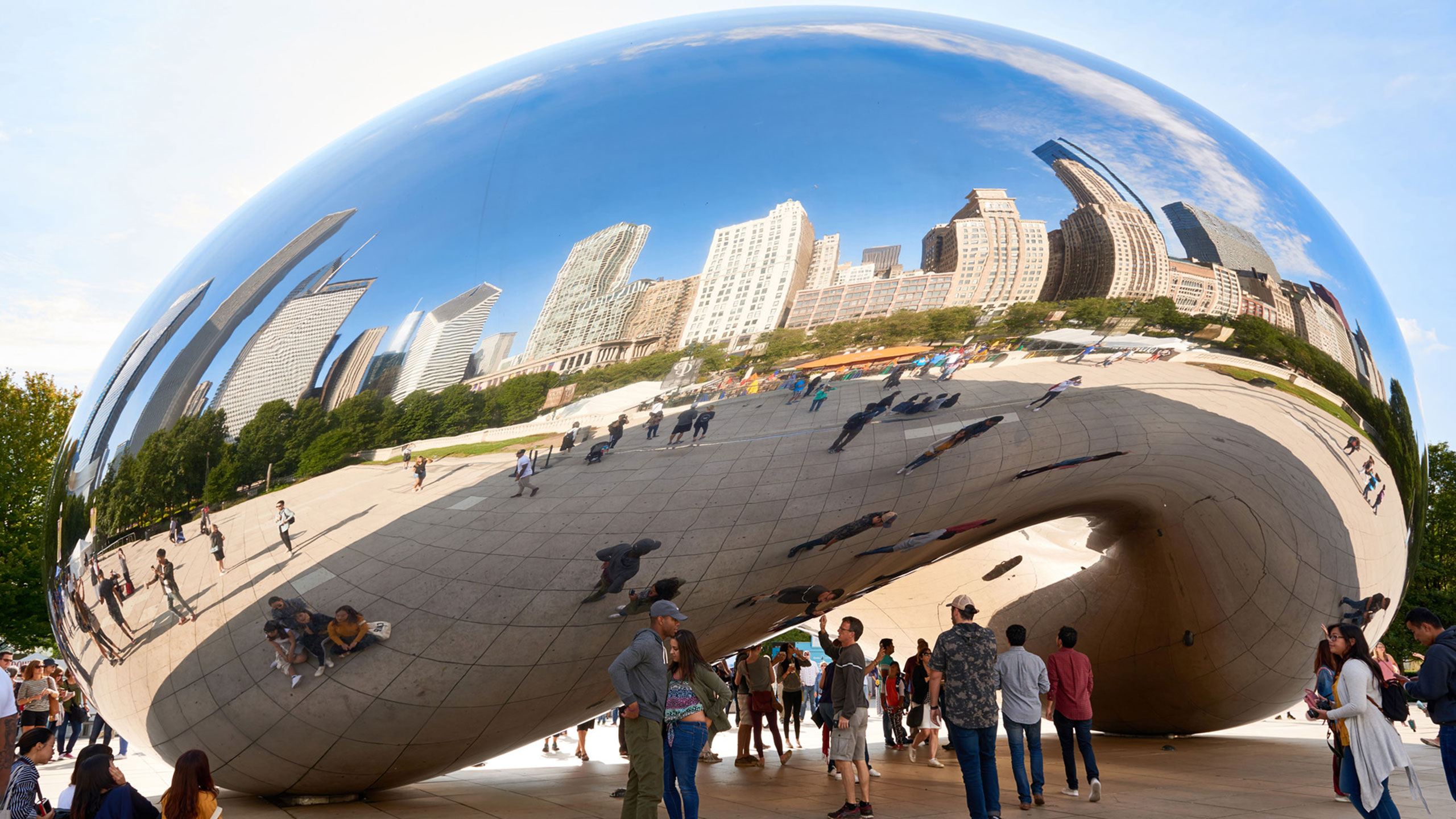 People stand under The Bean at Millennium Park in Chicago, Illinois