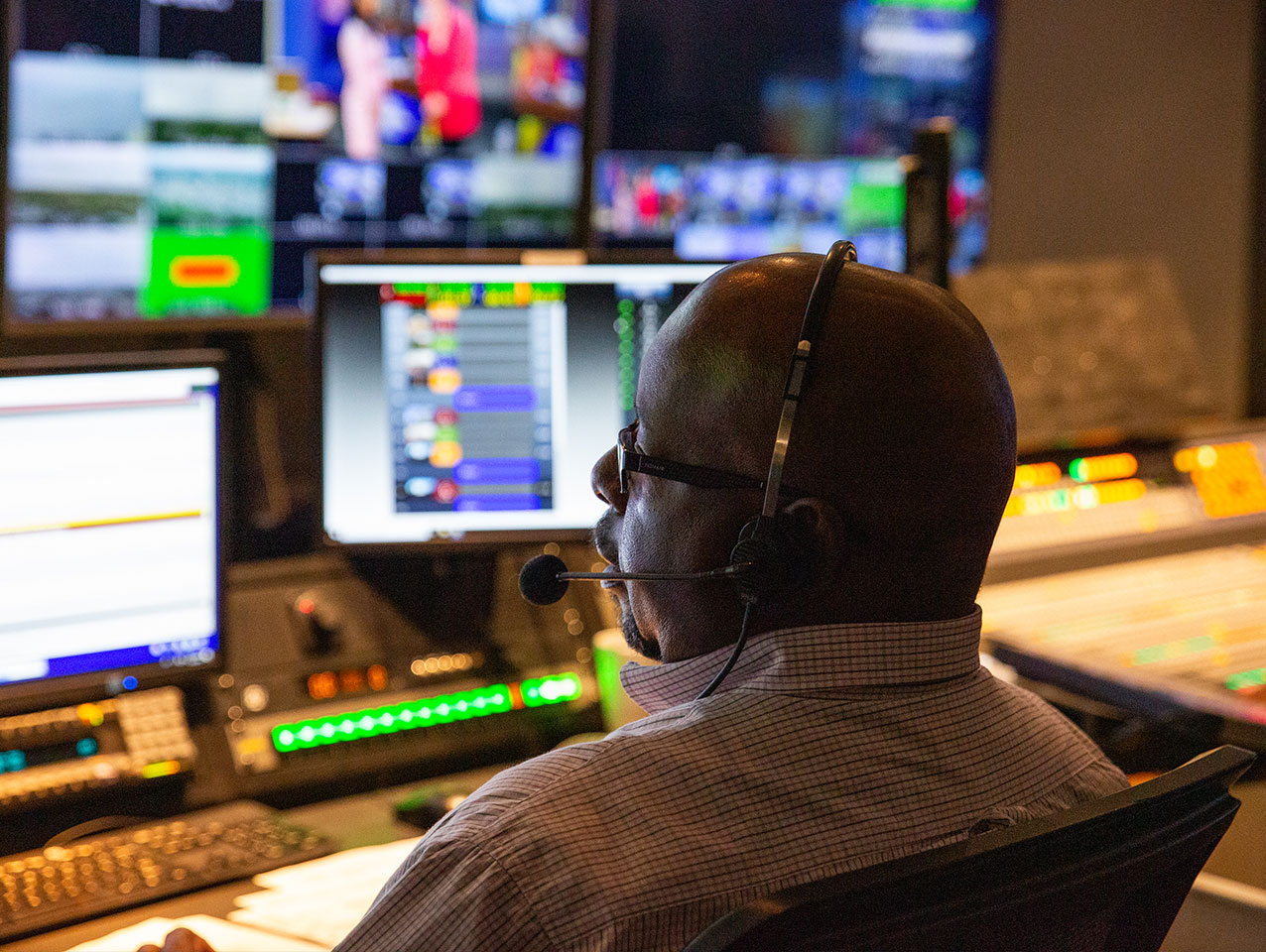 person sites in station control room with headset