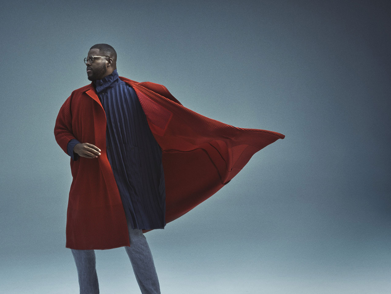 Man wearing long red coat billowing behind him