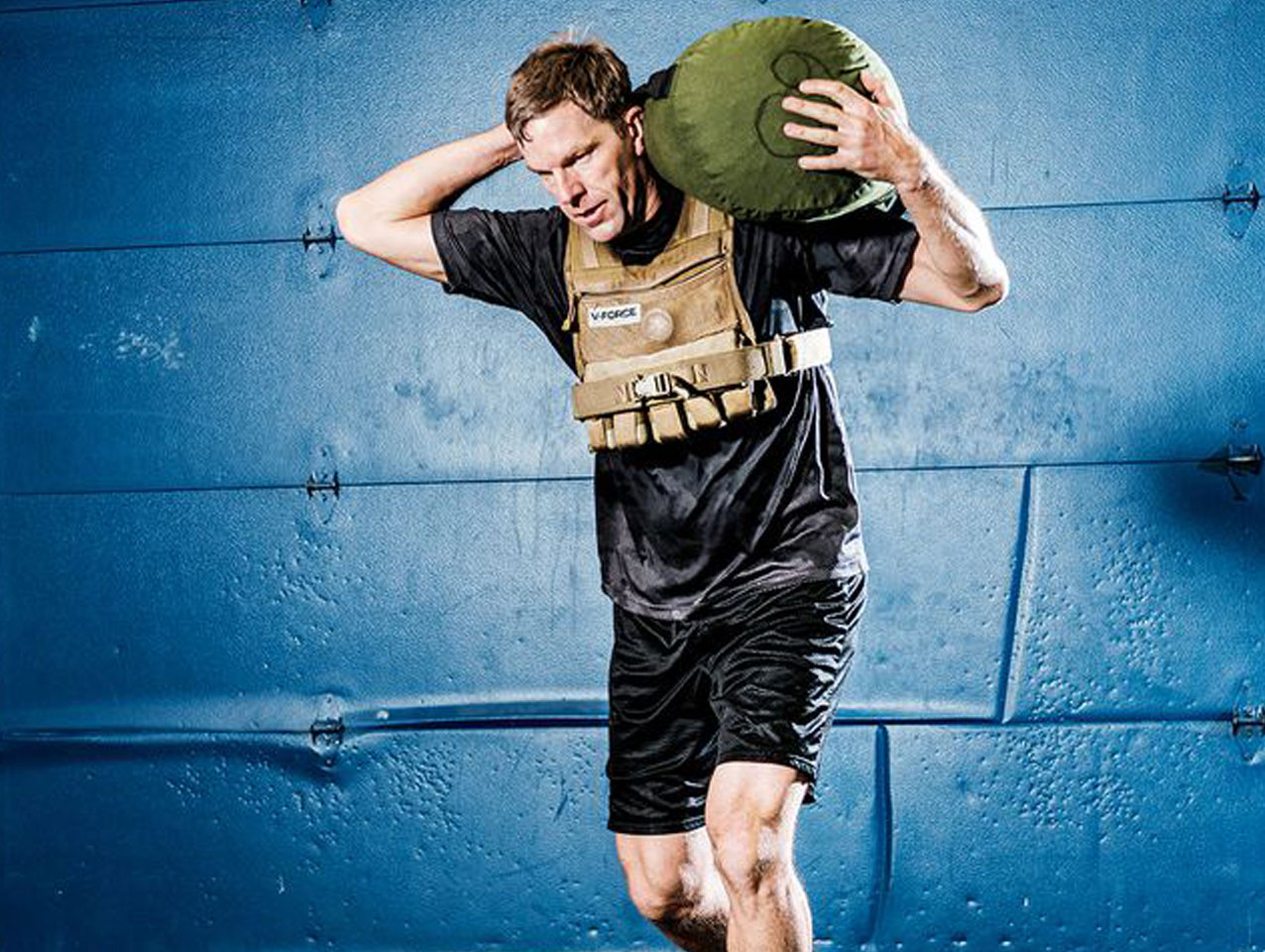 Man wearing vest carries heavy bag on his back