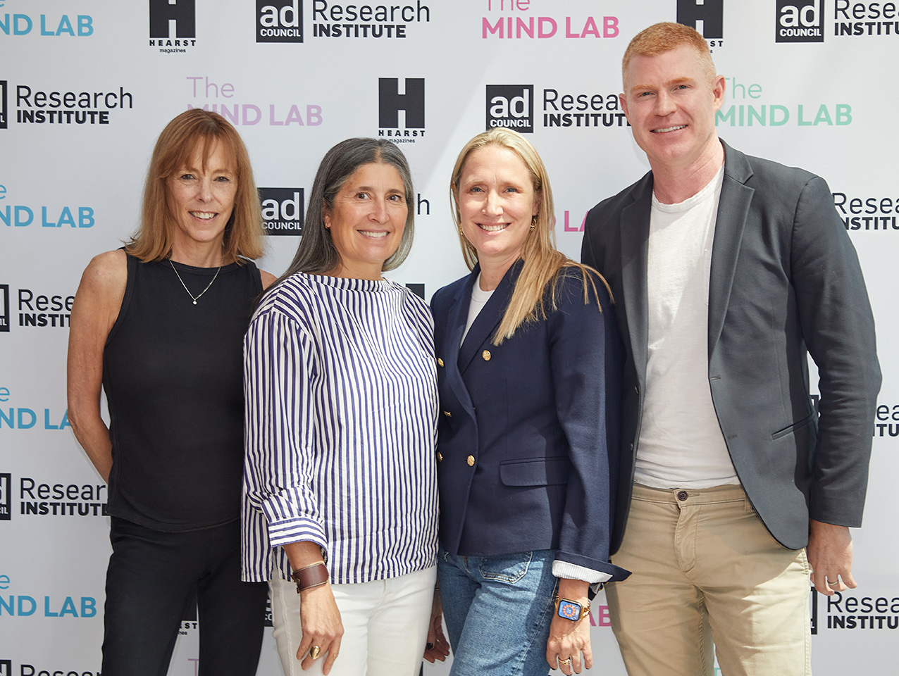 Four attendees of the MindLab event pose and smile against step & repeat