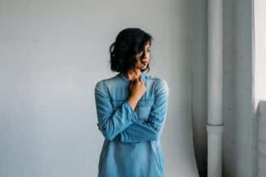 A woman stands alone in an empty room, highlighting how she feels depressed.