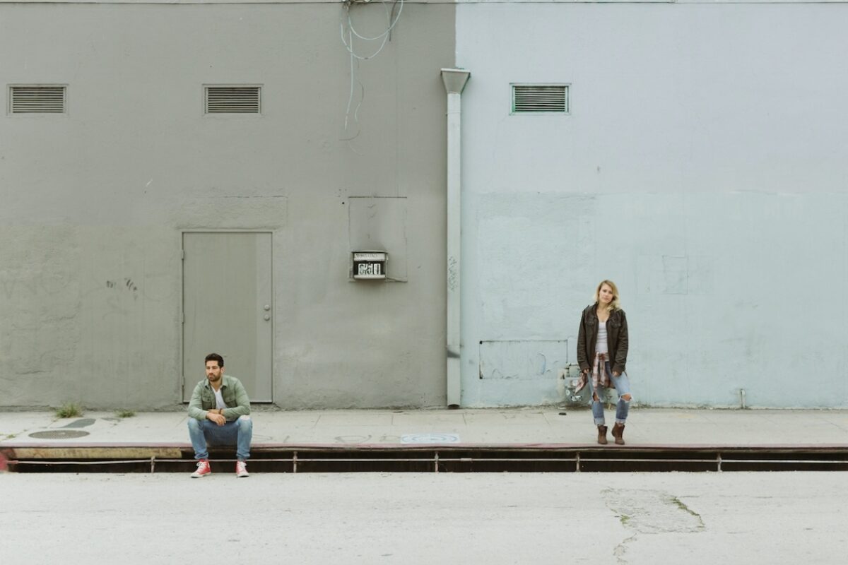 A man and a woman spaced apart in front of a building, indicating the nature of their adult attachment styles.