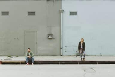 A man and a woman spaced apart in front of a building, indicating the nature of their adult attachment styles.