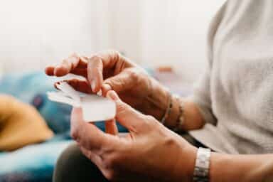 A woman's hands reach for her bipolar disorder medication from a clear plastic box