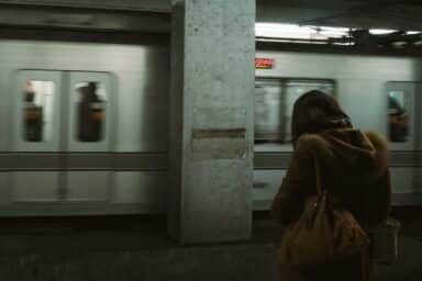 A woman stands forlornly in front of a subway train, illustrating her clinical depression, one of several types of depression.