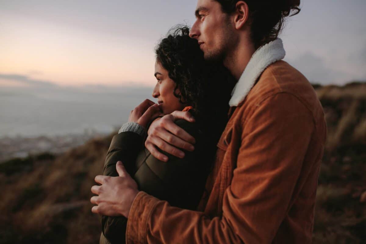 A couple embraces on a hilltop at sunset, embodying a healthy relationship.