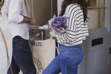 Woman holding bunch of purple flowers talking to a man