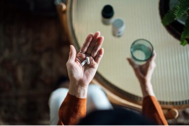 A woman with dietary supplements in her hand, illustrating a moment of contemplation regarding her health choices.