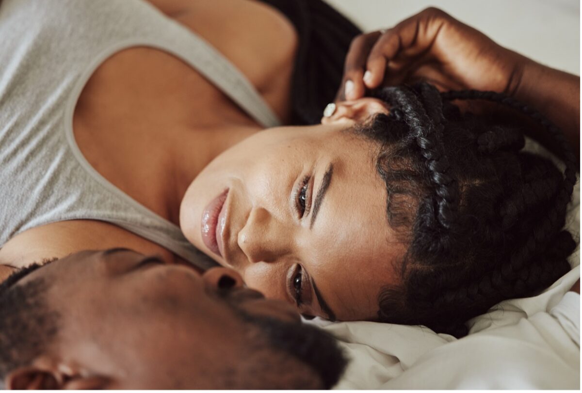 A man and woman peacefully lying in bed together, sharing a moment of intimacy and comfort.