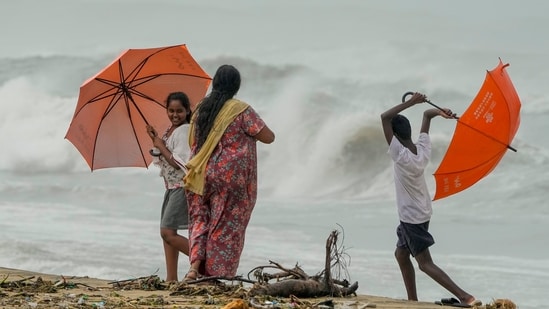 Locals visit the Marina Beach as high tidal waves lash the shore owing to Cyclone Michaung in Chennai, (PTI)