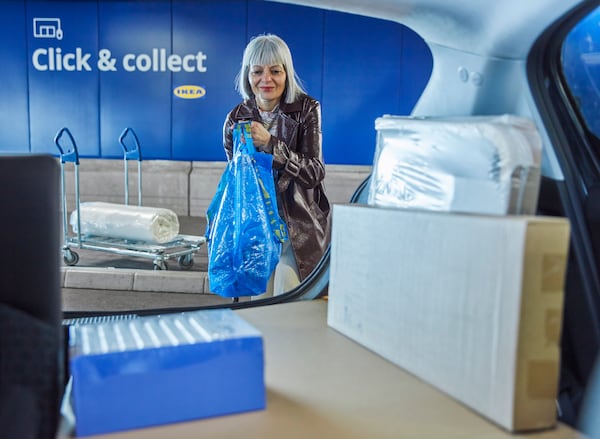 Woman putting click and collect purchases into the boot of her car