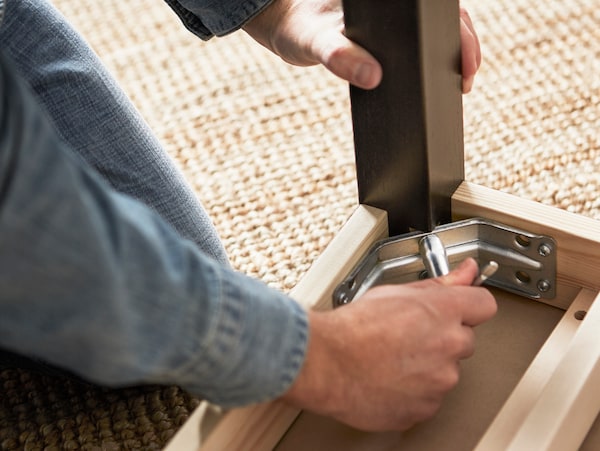 A person screwing legs onto a table top.