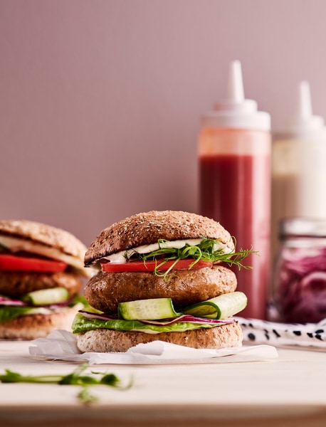 A burger, made from HUVUDROLL plant balls minced, with cucumber, red onion, lettuce, tomato, sprouts and mayonnaise.