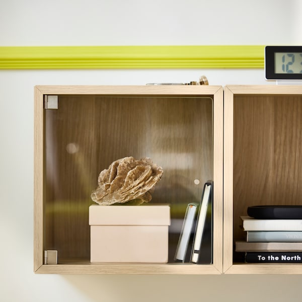 Close-up of two wall-mounted EKET cabinets in white stained oak, used as bedside table.