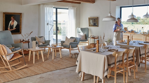 A large and bright living and dining space in traditional style with wooden beams in the ceiling and concrete floors.