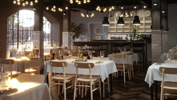 Several well-laid TOMMARYD tables with white table cloths, clear glasses and flowers in a spacious restaurant.