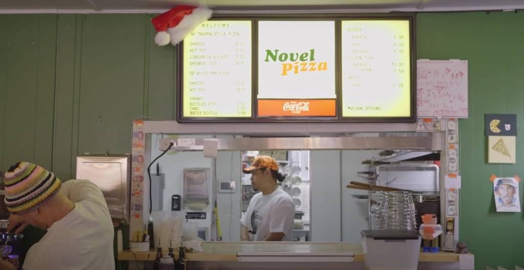 The window to order opens into the kitchen at Novel Pizza. Still from video.