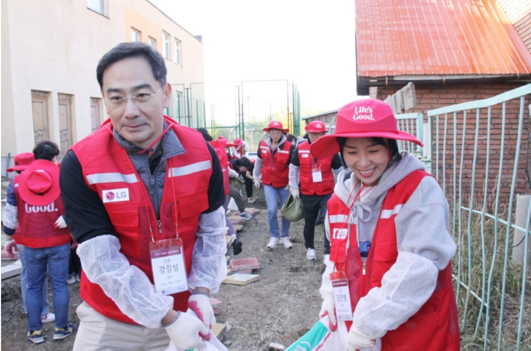 Two Life's Good volunteers carrying a heavy sac together