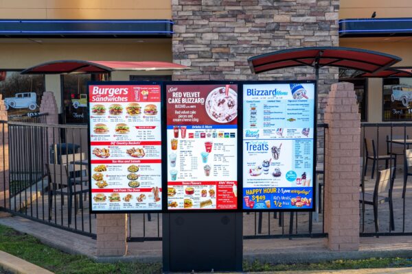 A photo of a digital sinage with a burger menu and drink menu