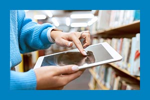 arms and hands of person wearing blue sweater using an ipad