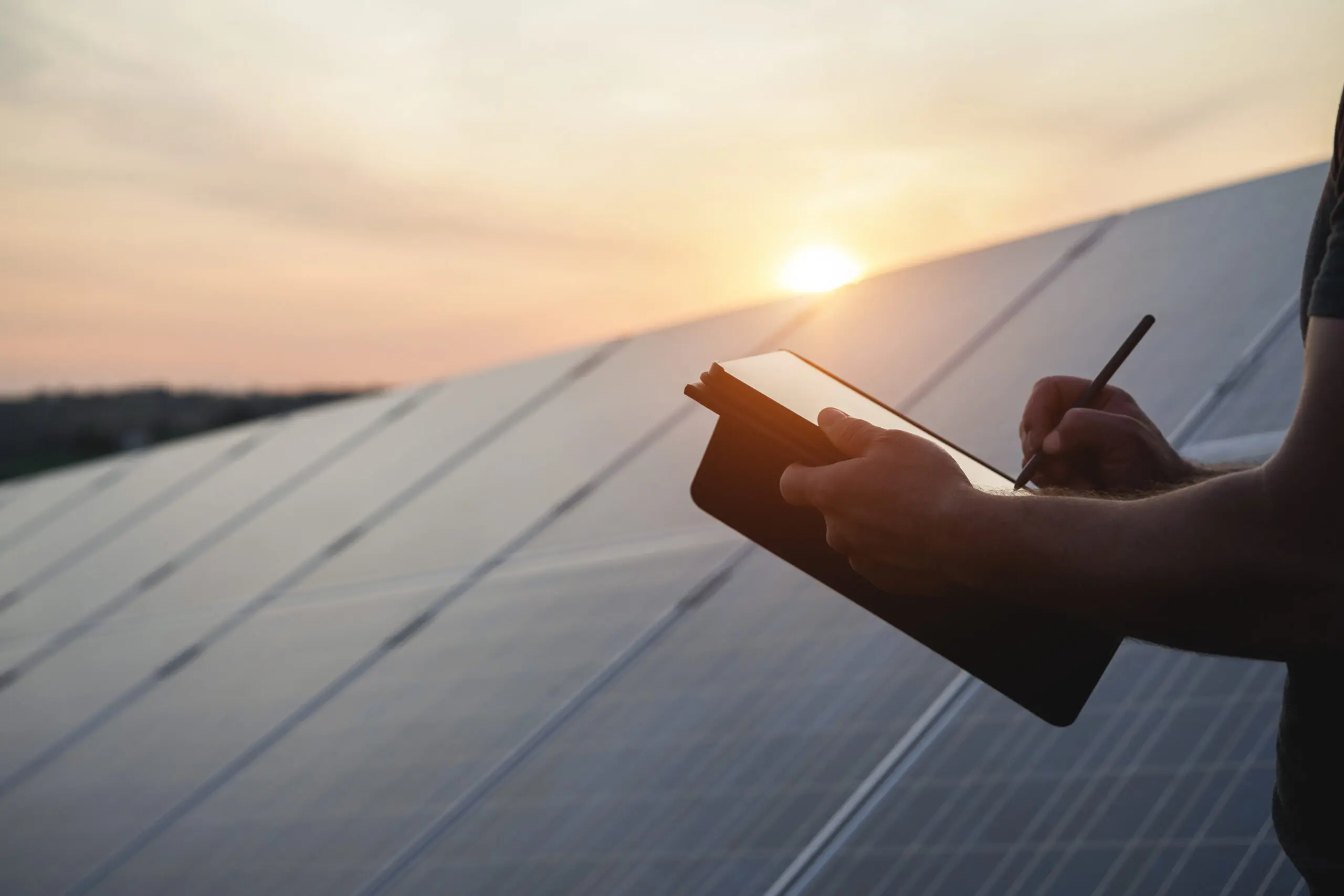 Engineer working at solar panels factory outdoor - Photovoltaic, renewable green energy and environmental concept - Focus left hand