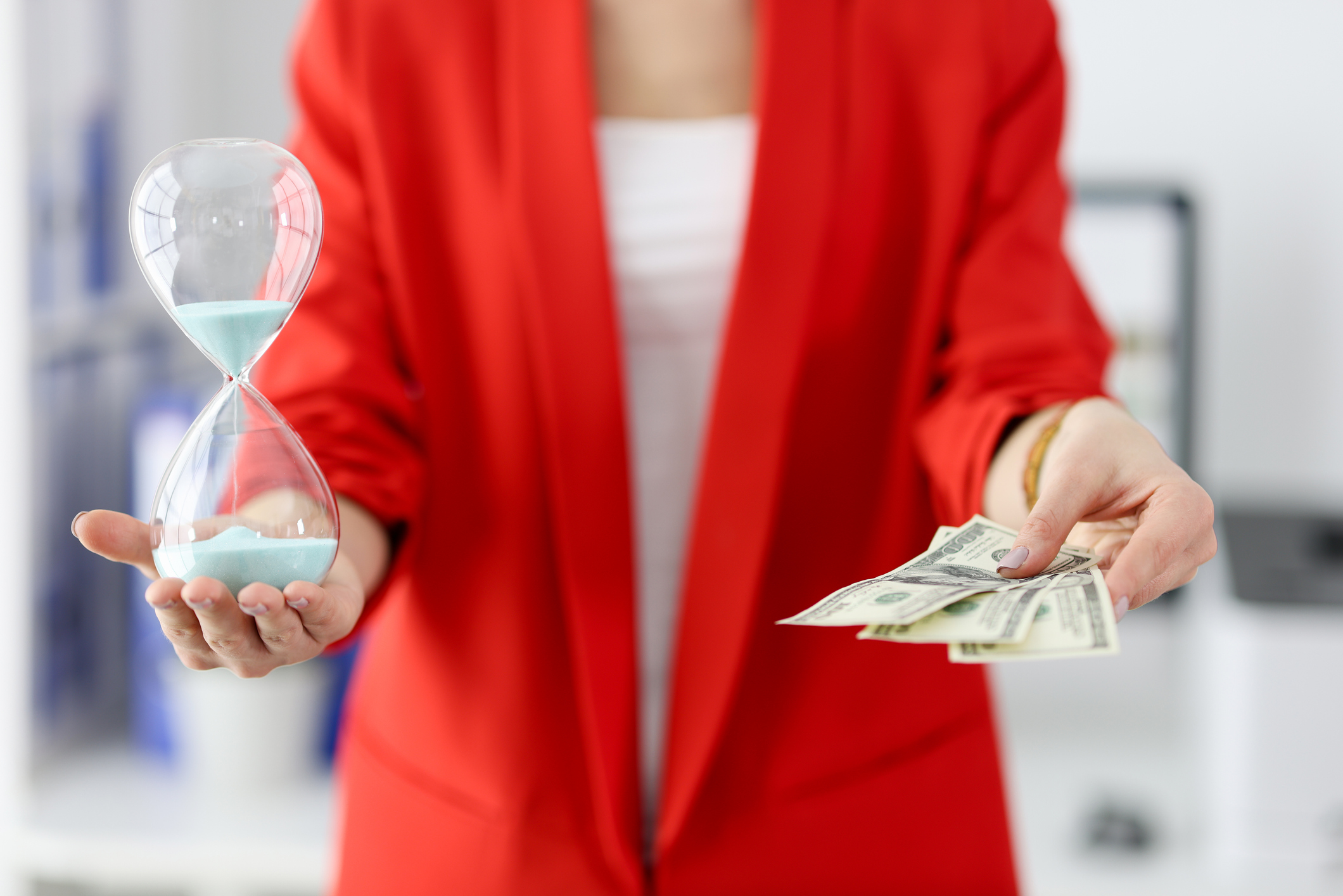 Businesswoman holds an hourglass and one hundred dollar bills in her hands. Time management in business concept