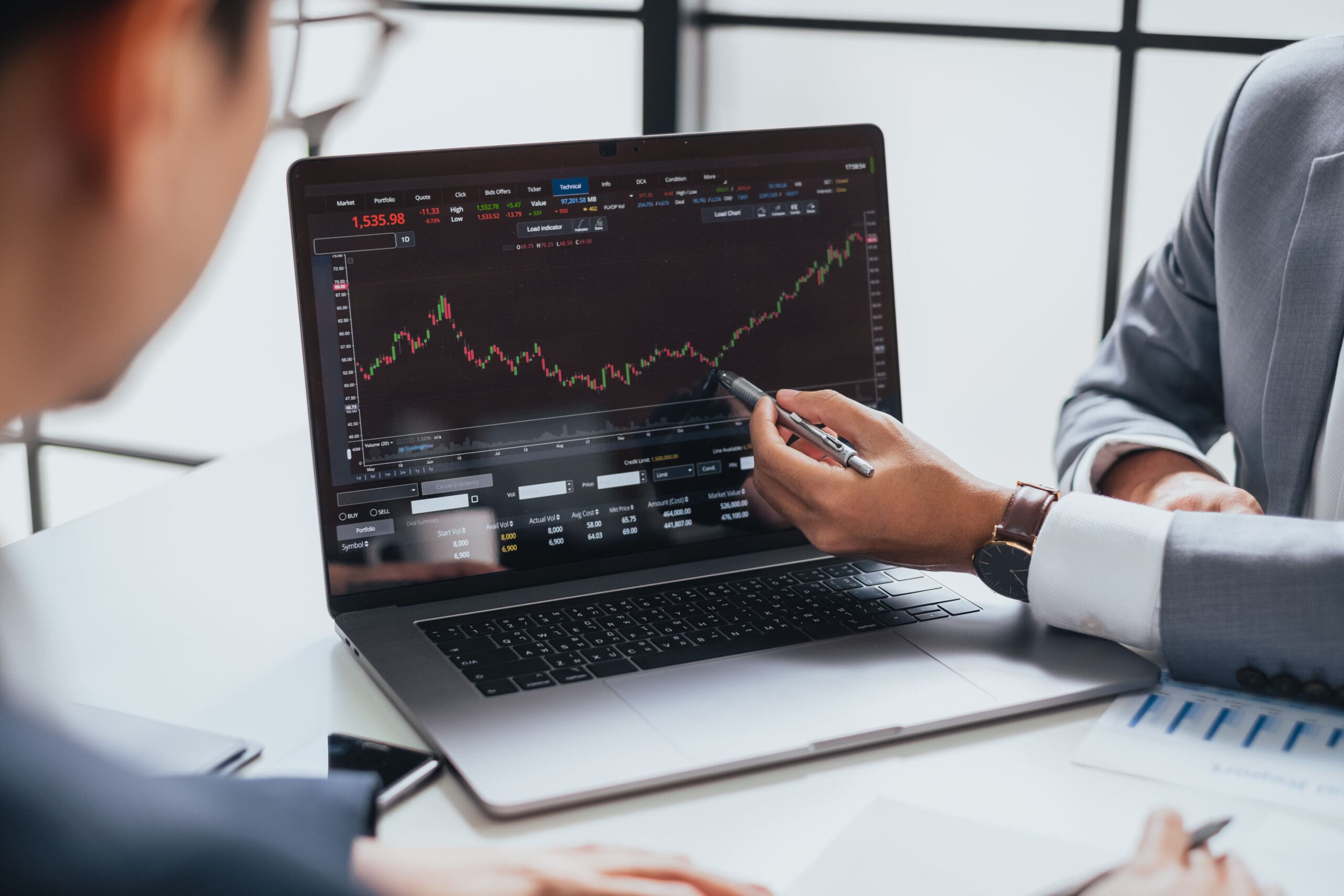 Businessman talking about investment stock market and graph from computer laptop with broker trader, giving money plan management and analysis. Depicts TradingView financial market chart.