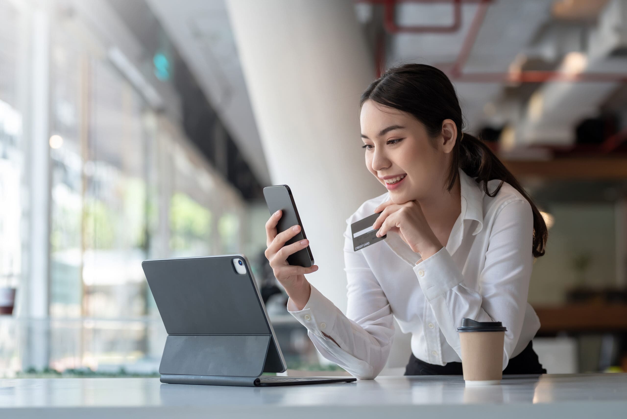 Young Asian businesswoman enjoy shopping online using credit card at a coffee shop.