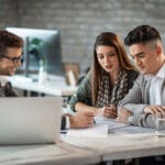 Young couple and bank manager reading financial reports while having a meeting in the office.