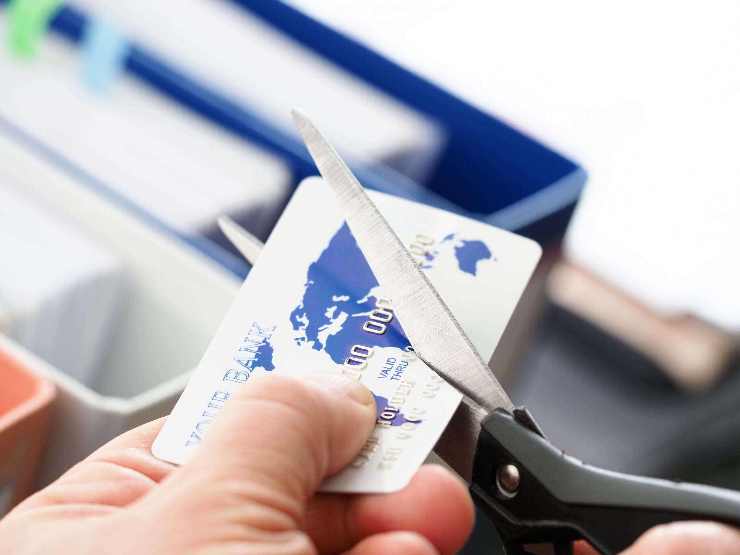 Male hand cutting banking card with scissors closeup