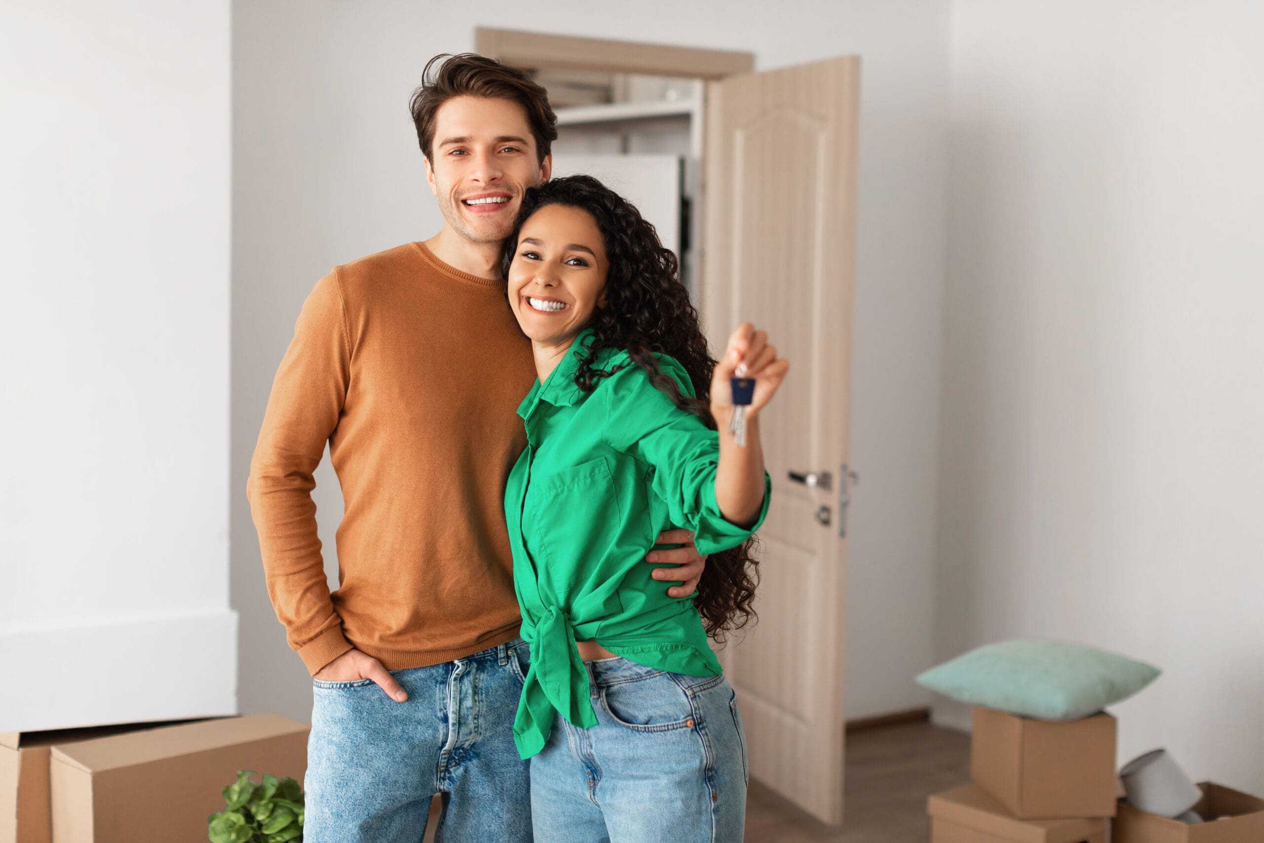 Happy couple showing keys that they own while moving into a house