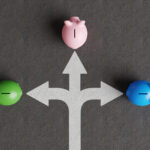 White divided road sign mark on asphalt with 3 different colored piggy banks going to different directions. Illustration of the concept of stock picks and varied investment products
