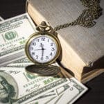 Still life image of pocket watch on bills and old book