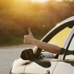 Man showing thumbs up from car window. Vacation and travel concept