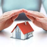 hands covering house - insurance concept - real estate