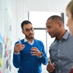 Multi-ethnic group hipster trendy business people with Indian boss discussing during a brainstorm session for their small company