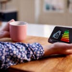 Close Up Of Woman Holding Smart Energy Meter In Kitchen Measuring Energy Efficiency