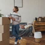 Smiling man standing by cardboard boxes at home