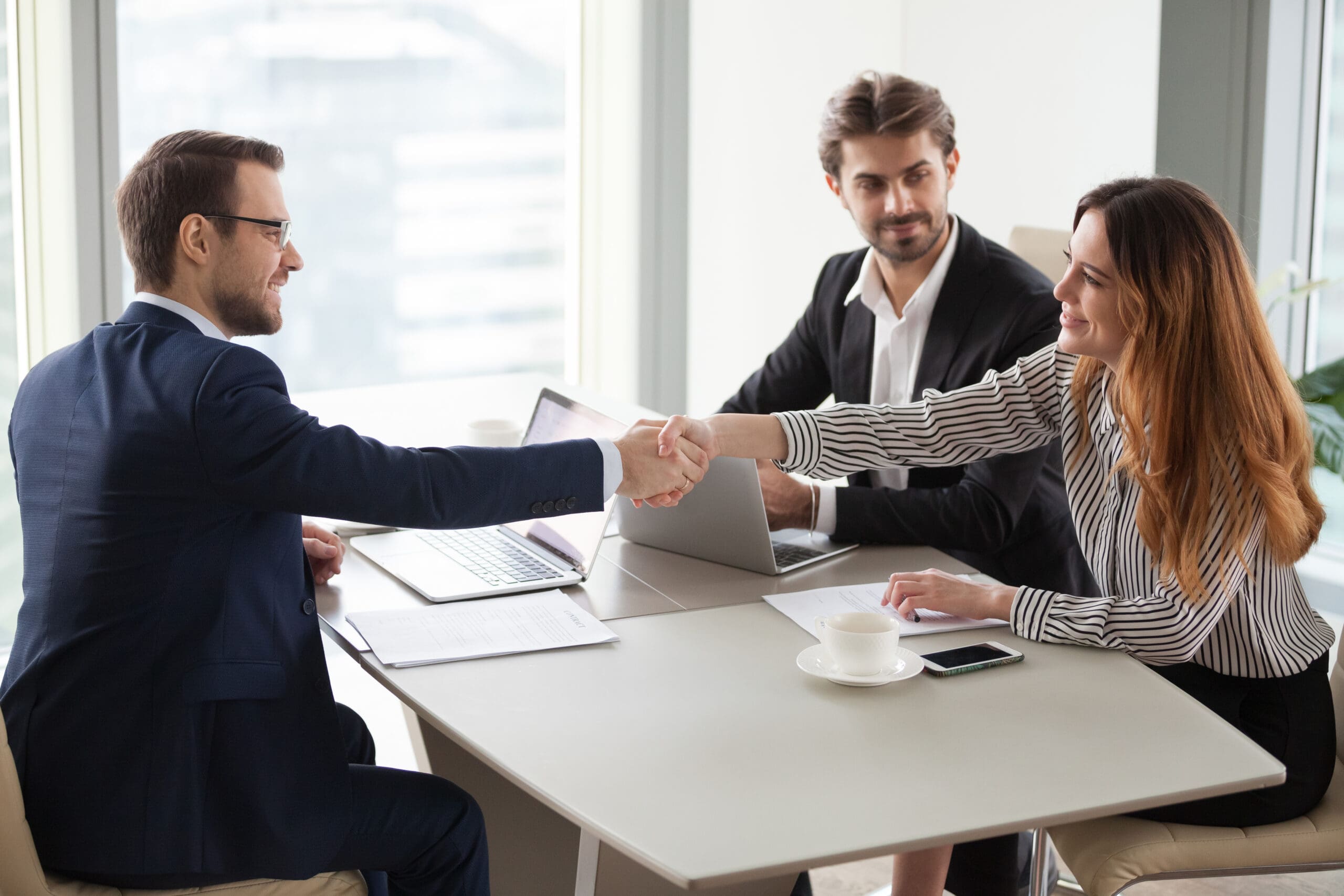 Businessman handshaking businesswoman making deal finishing group negotiations, satisfied smiling business partners conclude contract agreement shake hands expressing respect thank for group meeting