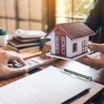 Investors are using st pen on the contract paper about buying a new home while filing cash as a deposit for the agent.