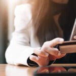 Close up female hands holding credit card and smartphone, young woman paying online, using banking service, entering information, shopping, ordering in internet store, doing secure payment