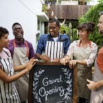 Group of friends with grand opening board together