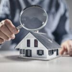 House with ith man holding magnifying glass concept for home inspection or searching for a new house