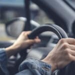 Tense hands of a female driver on the steering wheel in a car. Stress while driving a car concept