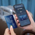 female hands hold phone with airplane ticket application airlines on screen and credit card on background of luggage at airport