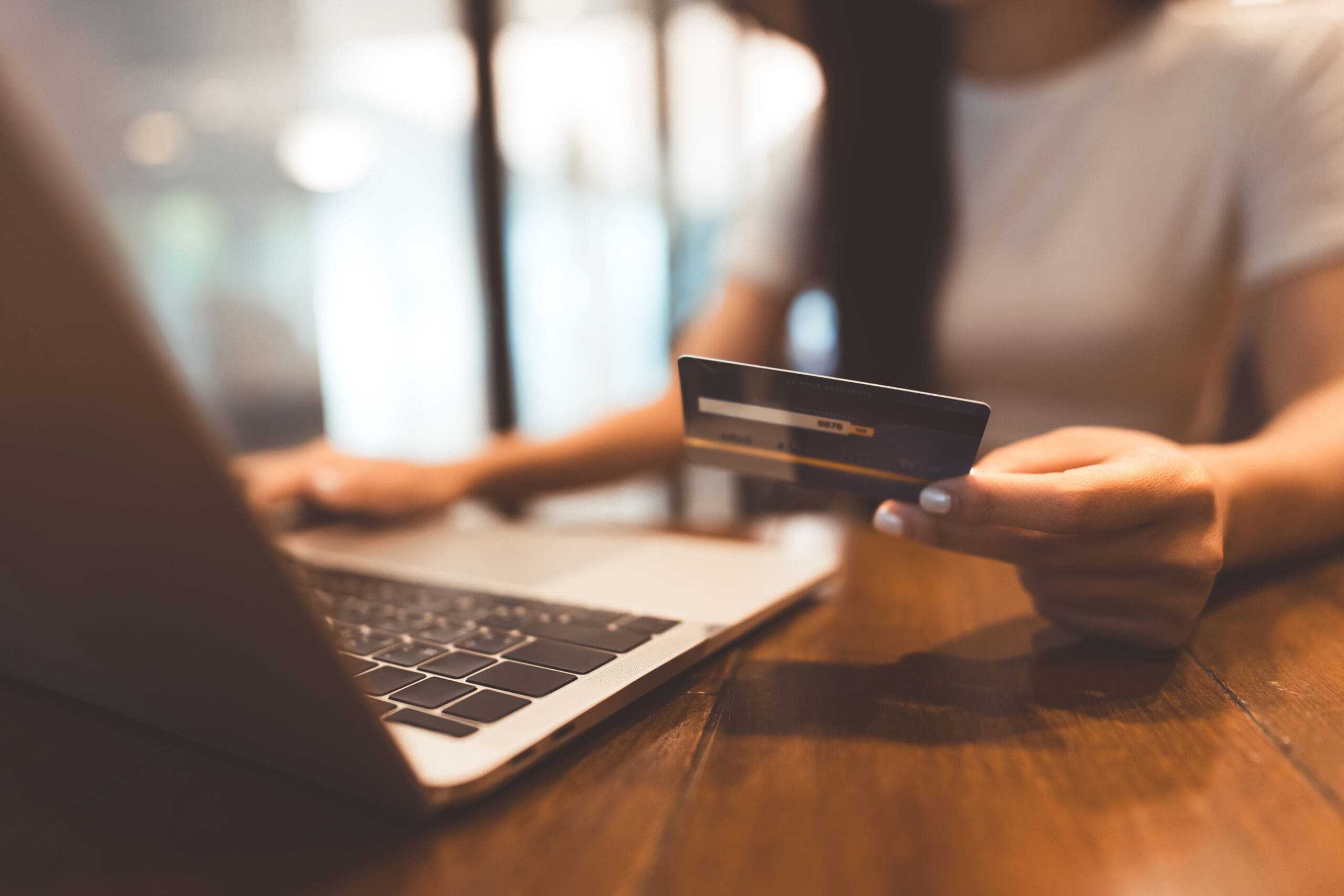 Business people shopping via online payment and digital wallet concept. Woman hand consumer using creadit card or debit and laptop on wooden table.