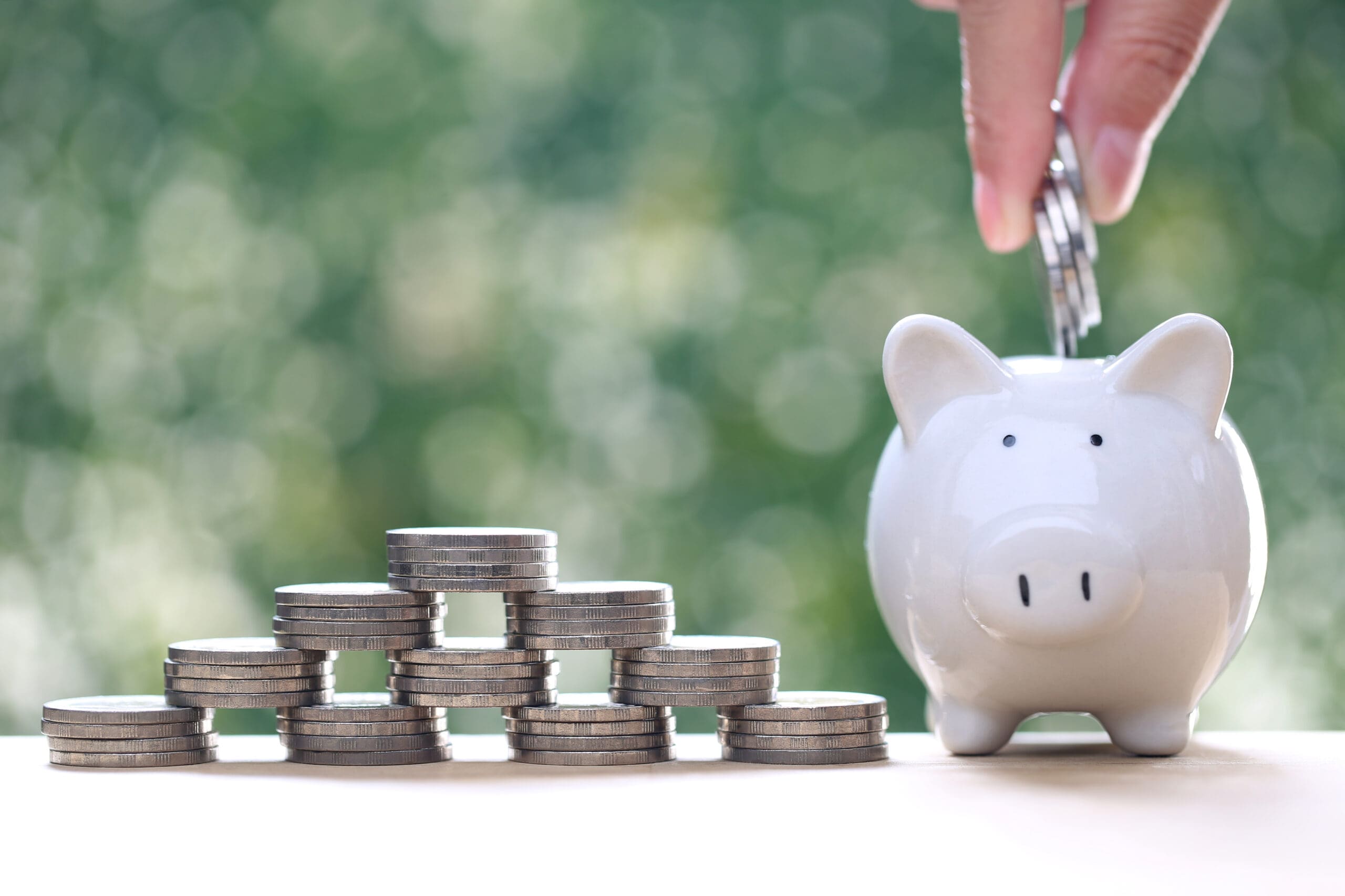 Piggy bank and stack of coins money on natural green background, Save money for prepare in future and pension retirement concept